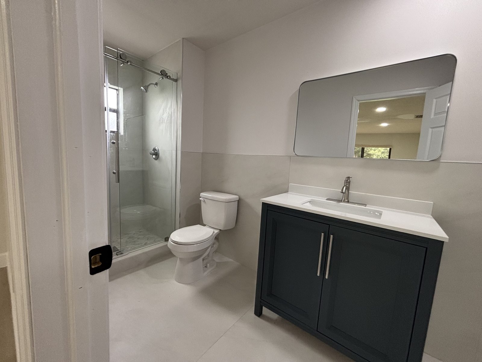 Renovated bathroom with glass shower, new vanity, and mirror